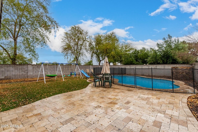 view of pool featuring a patio, a playground, and a fenced backyard