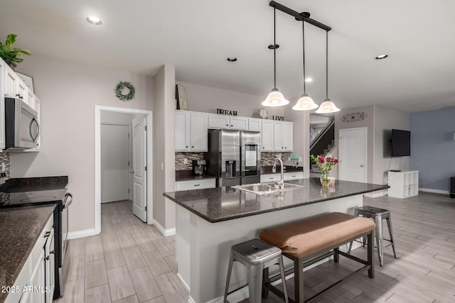 kitchen with tasteful backsplash, a kitchen bar, appliances with stainless steel finishes, white cabinetry, and a sink