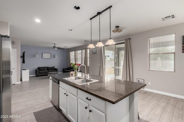 kitchen featuring visible vents, stainless steel appliances, a sink, white cabinetry, and open floor plan