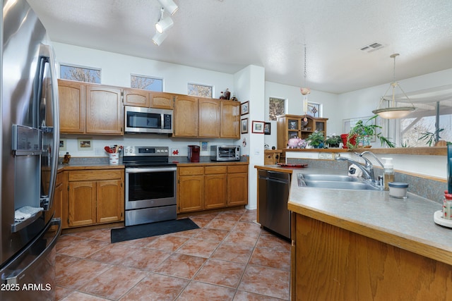 kitchen featuring a wealth of natural light, a textured ceiling, stainless steel appliances, and a sink