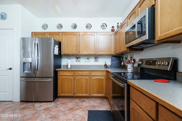 kitchen featuring brown cabinets, light tile patterned floors, stainless steel appliances, and light countertops