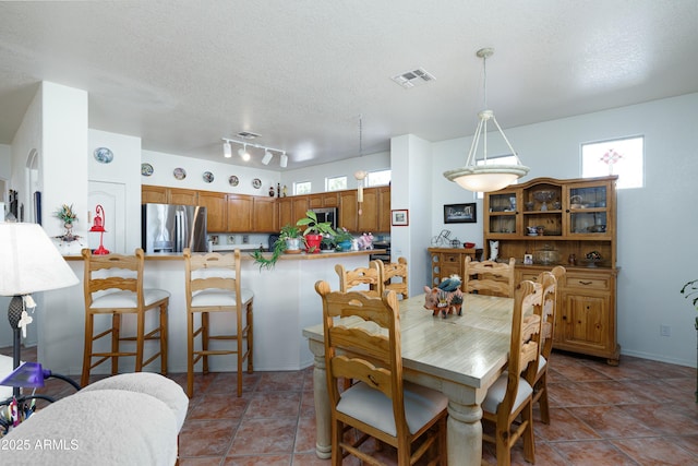 tiled dining area with visible vents and a textured ceiling