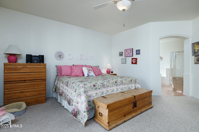 carpeted bedroom with arched walkways and a ceiling fan