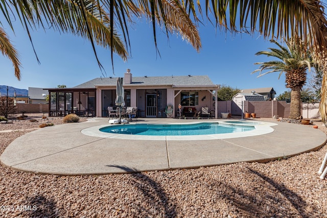 view of pool with a sunroom, a fenced backyard, an outdoor structure, a patio area, and a shed