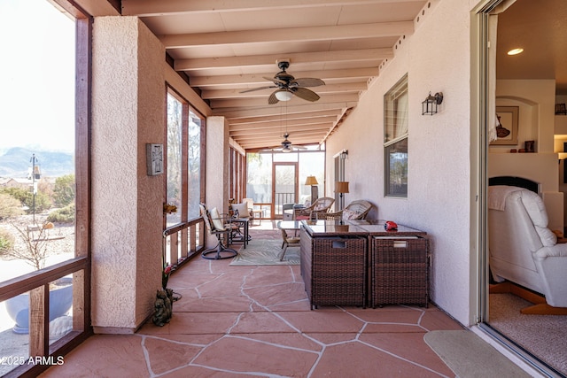 sunroom featuring beamed ceiling and a ceiling fan