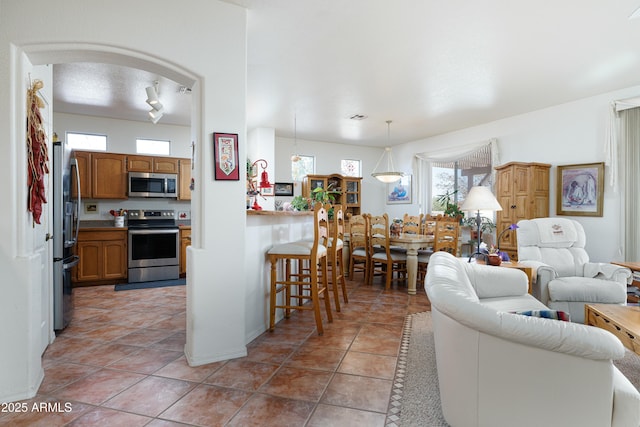 living area with arched walkways, light tile patterned flooring, and visible vents