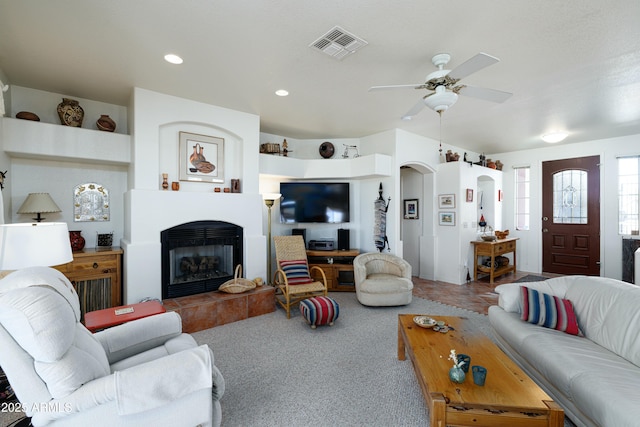 carpeted living area with arched walkways, ceiling fan, recessed lighting, a fireplace, and visible vents