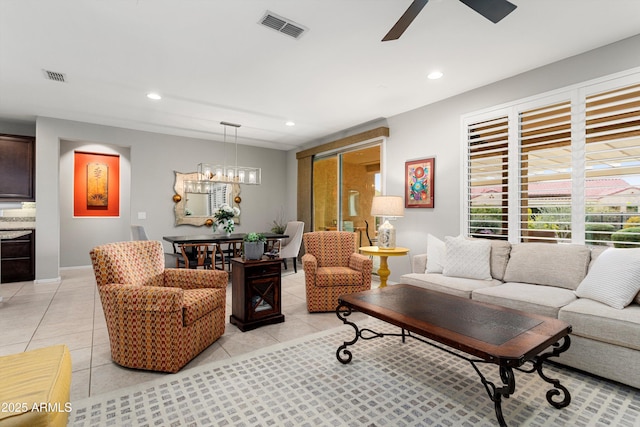 living area featuring light tile patterned floors, ceiling fan with notable chandelier, and visible vents