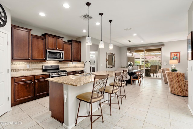 kitchen featuring light stone counters, decorative backsplash, stainless steel appliances, and a sink