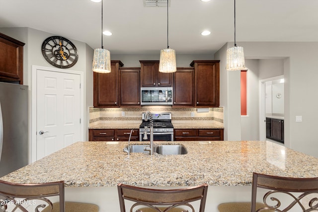 kitchen with a breakfast bar, backsplash, appliances with stainless steel finishes, and pendant lighting