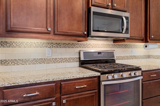 kitchen featuring light stone counters, decorative backsplash, and stainless steel appliances