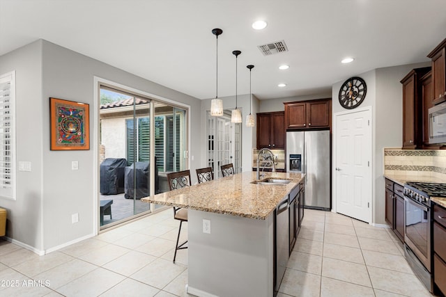 kitchen with light tile patterned floors, visible vents, a sink, stainless steel appliances, and a kitchen breakfast bar