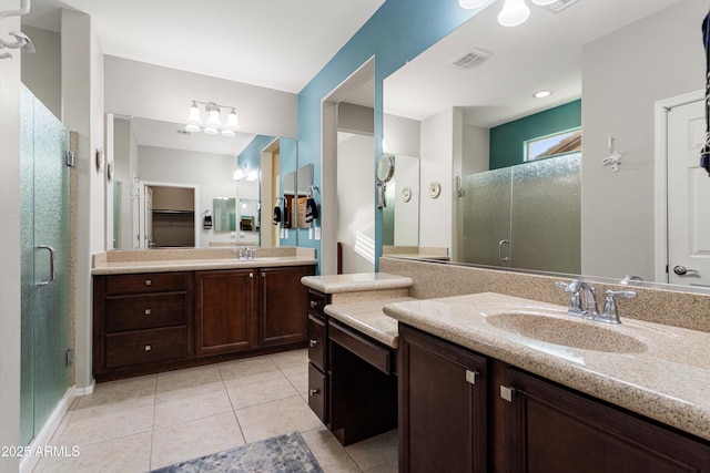 full bath with visible vents, a shower stall, two vanities, and a sink