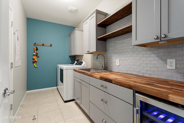 laundry area featuring washing machine and clothes dryer, light tile patterned flooring, cabinet space, a sink, and wine cooler