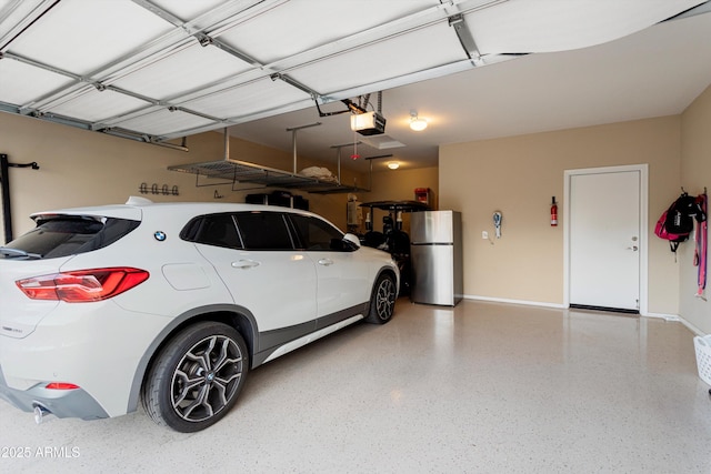 garage featuring a garage door opener, baseboards, and freestanding refrigerator