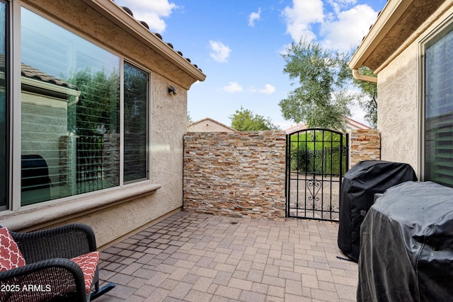 view of patio / terrace featuring a grill, fence, and a gate