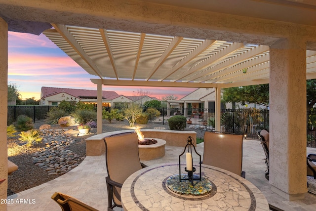 patio terrace at dusk with outdoor dining space, a fenced backyard, a pergola, and a fire pit