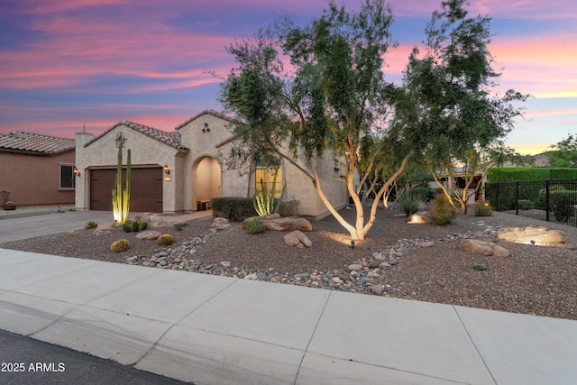 view of front of property featuring fence, a tiled roof, concrete driveway, stucco siding, and a garage