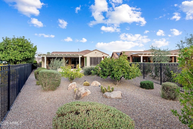 rear view of property with stucco siding, a fenced backyard, and a tile roof