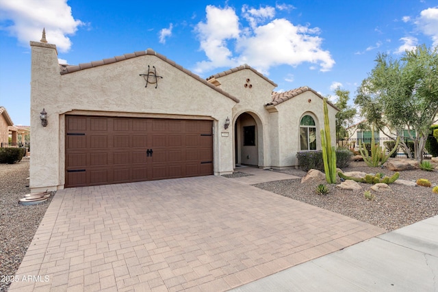 mediterranean / spanish house with decorative driveway, an attached garage, and stucco siding