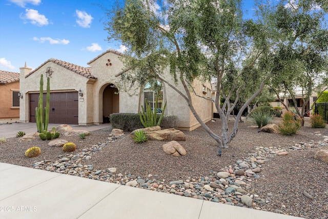 view of front facade featuring stucco siding, driveway, an attached garage, and a tile roof