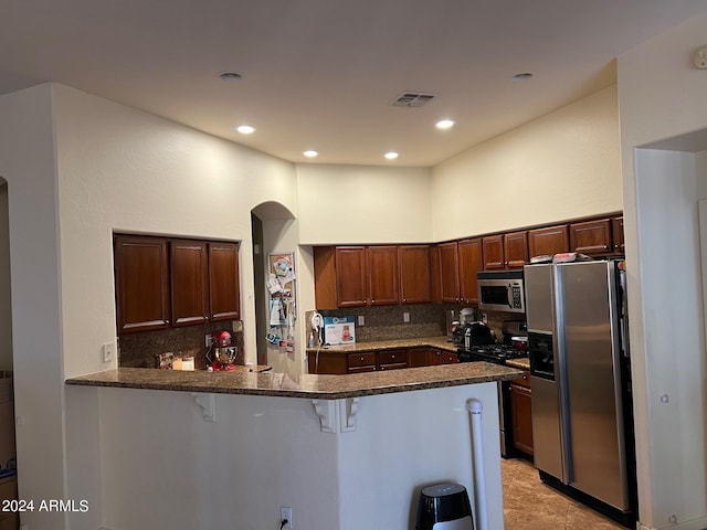 kitchen with appliances with stainless steel finishes, kitchen peninsula, a kitchen breakfast bar, and tasteful backsplash