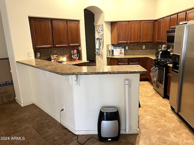 kitchen featuring backsplash, kitchen peninsula, a kitchen bar, and stainless steel appliances