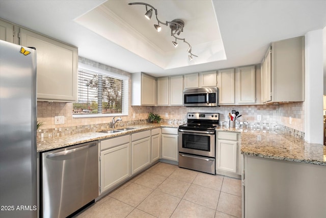 kitchen with a sink, a raised ceiling, tasteful backsplash, and appliances with stainless steel finishes