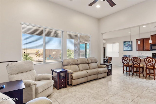 tiled living room featuring a high ceiling, a wealth of natural light, and ceiling fan