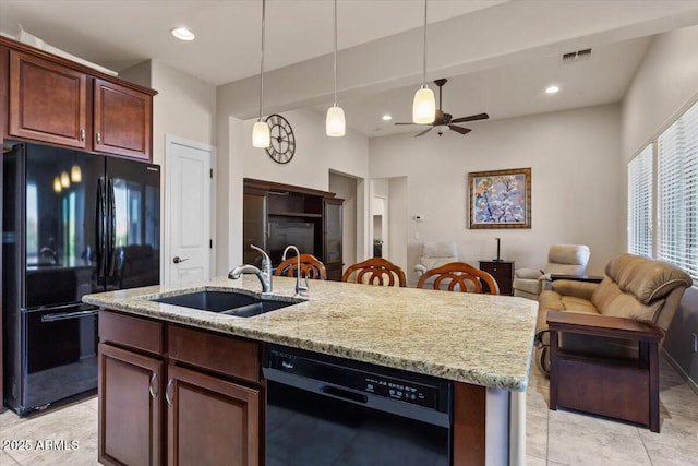 kitchen with pendant lighting, sink, black appliances, and light stone countertops