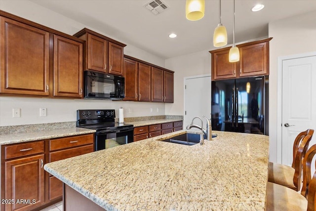 kitchen featuring a kitchen breakfast bar, a kitchen island with sink, sink, and black appliances