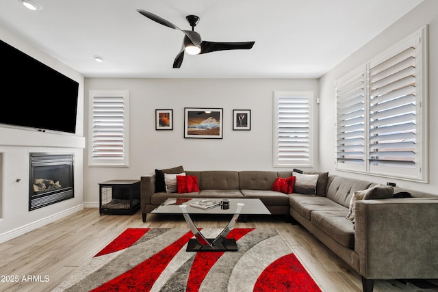 4976 E Thunderbird Dr, Chandler, AZ 85249 - living area featuring wood finished floors, a glass covered fireplace, a ceiling fan, and baseboards