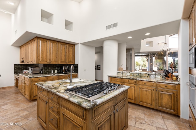 kitchen with an inviting chandelier, appliances with stainless steel finishes, light tile floors, and a towering ceiling