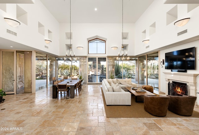 living room with light tile floors, a notable chandelier, and a towering ceiling