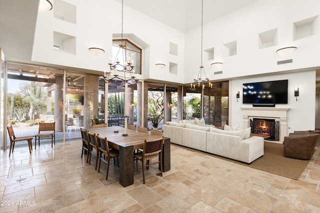 dining area featuring plenty of natural light, a chandelier, and a towering ceiling