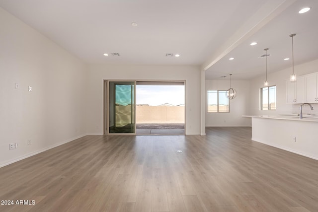 unfurnished living room featuring hardwood / wood-style flooring, a notable chandelier, and sink