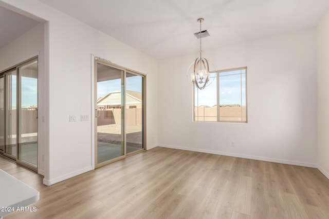 unfurnished room featuring a chandelier, light hardwood / wood-style floors, and a healthy amount of sunlight