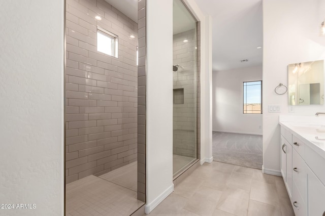 bathroom featuring tiled shower, vanity, a healthy amount of sunlight, and tile patterned flooring