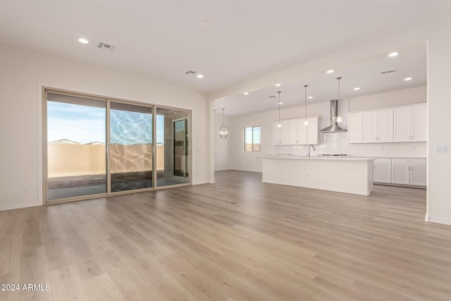 unfurnished living room with light hardwood / wood-style flooring and sink