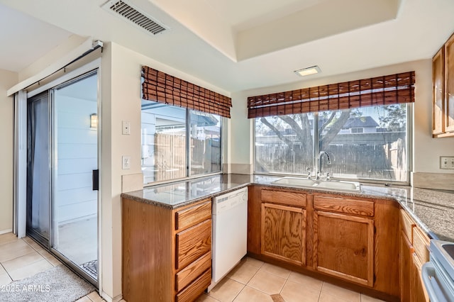 kitchen featuring light tile patterned floors, dishwasher, light stone countertops, stainless steel stove, and sink