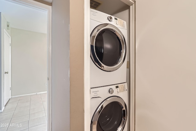 laundry room with light tile patterned floors and stacked washer / dryer