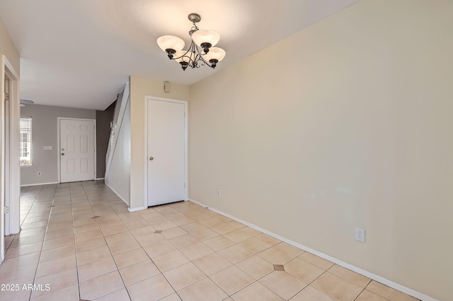 empty room featuring light tile patterned floors and an inviting chandelier