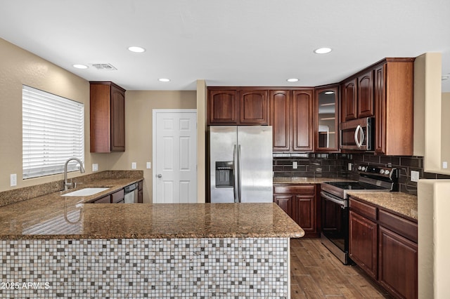 kitchen featuring dark wood-type flooring, stainless steel appliances, tasteful backsplash, sink, and kitchen peninsula