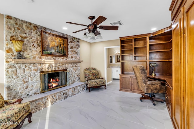 home office with a stone fireplace and ceiling fan