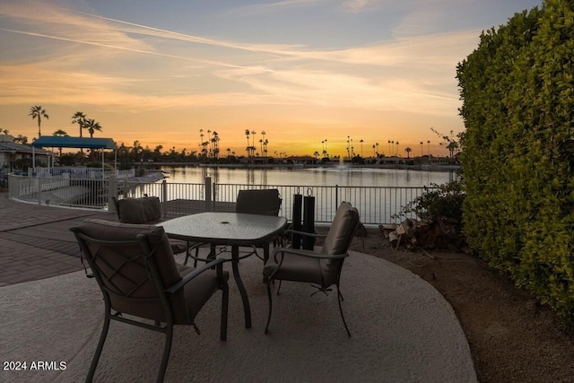 patio terrace at dusk with a boat dock and a water view