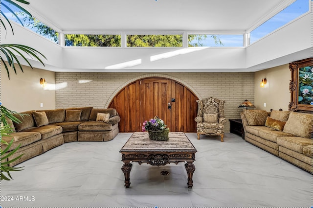 living room featuring brick wall and a high ceiling