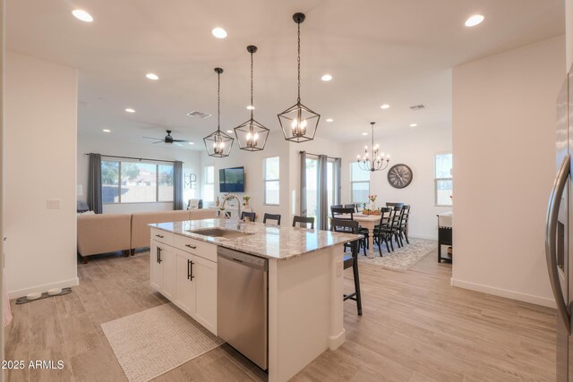 kitchen with sink, white cabinets, light stone counters, an island with sink, and stainless steel dishwasher