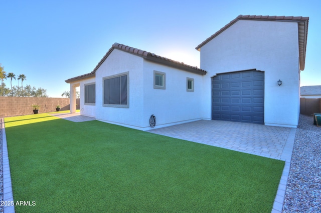 exterior space featuring a patio area, a front lawn, and a garage