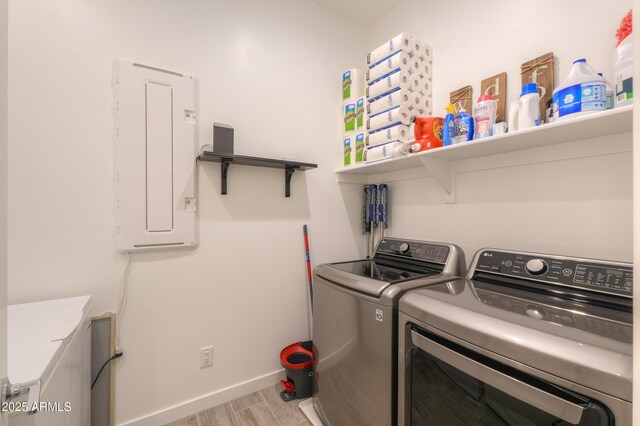 laundry room with washing machine and dryer, light wood-type flooring, and electric panel