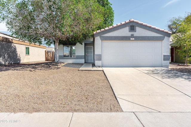 view of front facade featuring an attached garage, driveway, a tiled roof, and stucco siding